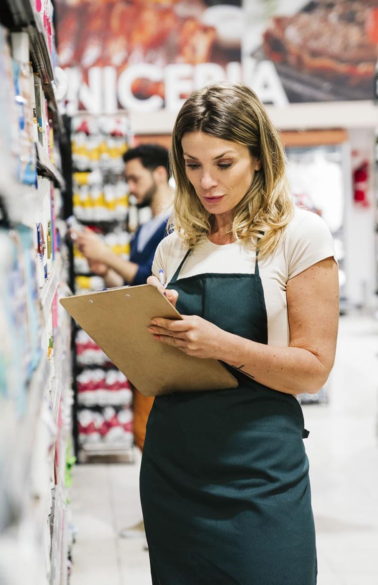 femail-store-cleark-checking-inventory2 A female store clerk wearing an apron holds a pen and clipboard as she crosses tasks off a checklist.